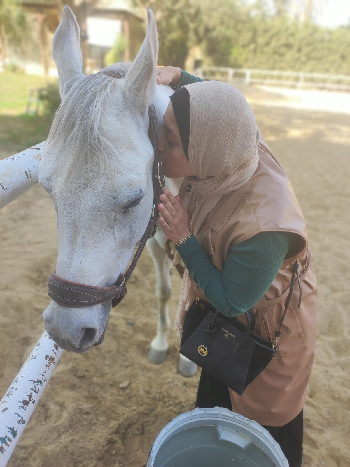 A woman resting her forehead against a white horse